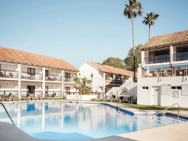 Una piscina al aire libre, sombrillas, tumbonas