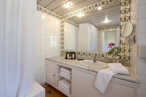 Un baño con un lavamanos blanco, un espejo y una cortina de ducha.