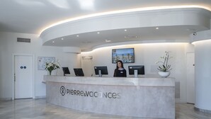 Un mostrador de recepción con un cartel que dice "Pierre & Vacances" en un moderno vestíbulo de hotel con techo curvo y un ventanal grande.