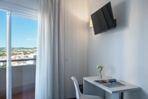 Una camera d'hotel moderna con un balcone, un tavolino con un vaso di fiori e una TV a parete.