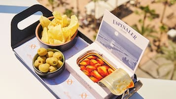 Una bandeja con aperitivos y un menú en un balcón con vista al mar.