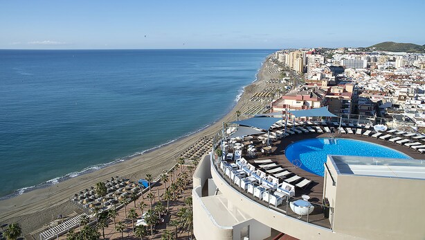 Un resort con piscina, playa y vista a la ciudad.