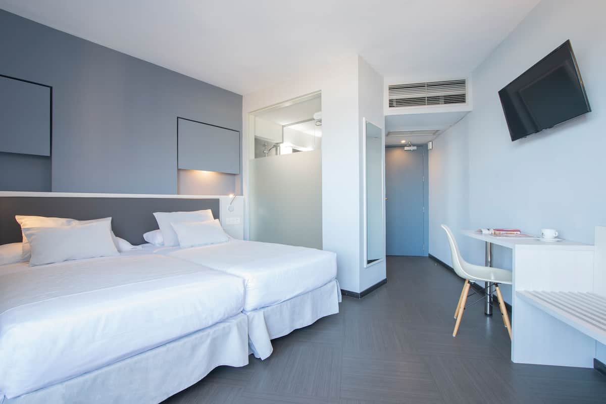 Een moderne hotelkamer met twee bedden, een bureau, een stoel, een televisie en een spiegel.