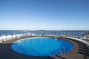 Een buitenzwembad, ligstoelen bij het zwembad