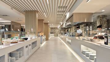 A modern kitchen with a long counter, stainless steel appliances, and a chef preparing food.