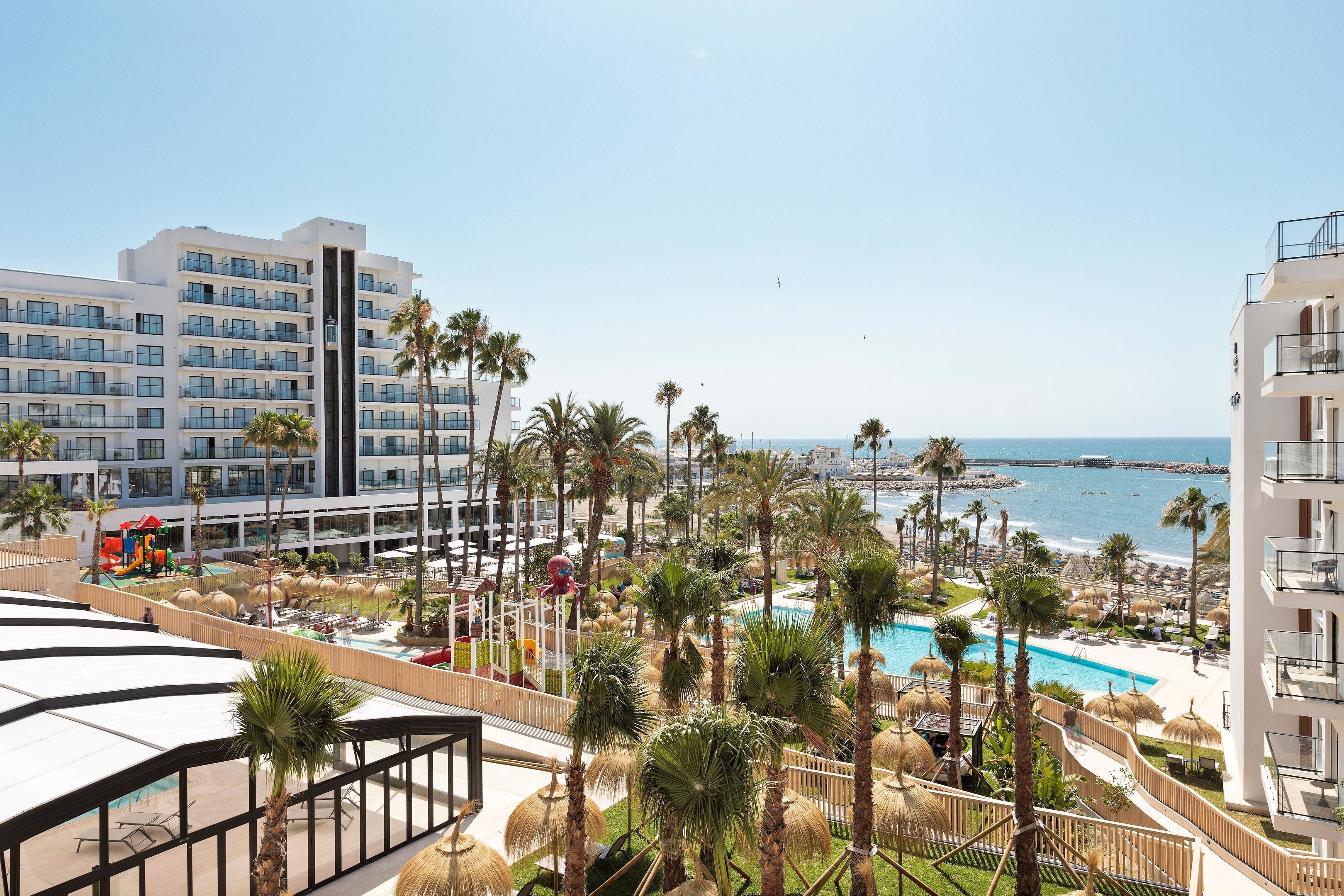 Un resort con piscina, palmeras y vistas al océano.