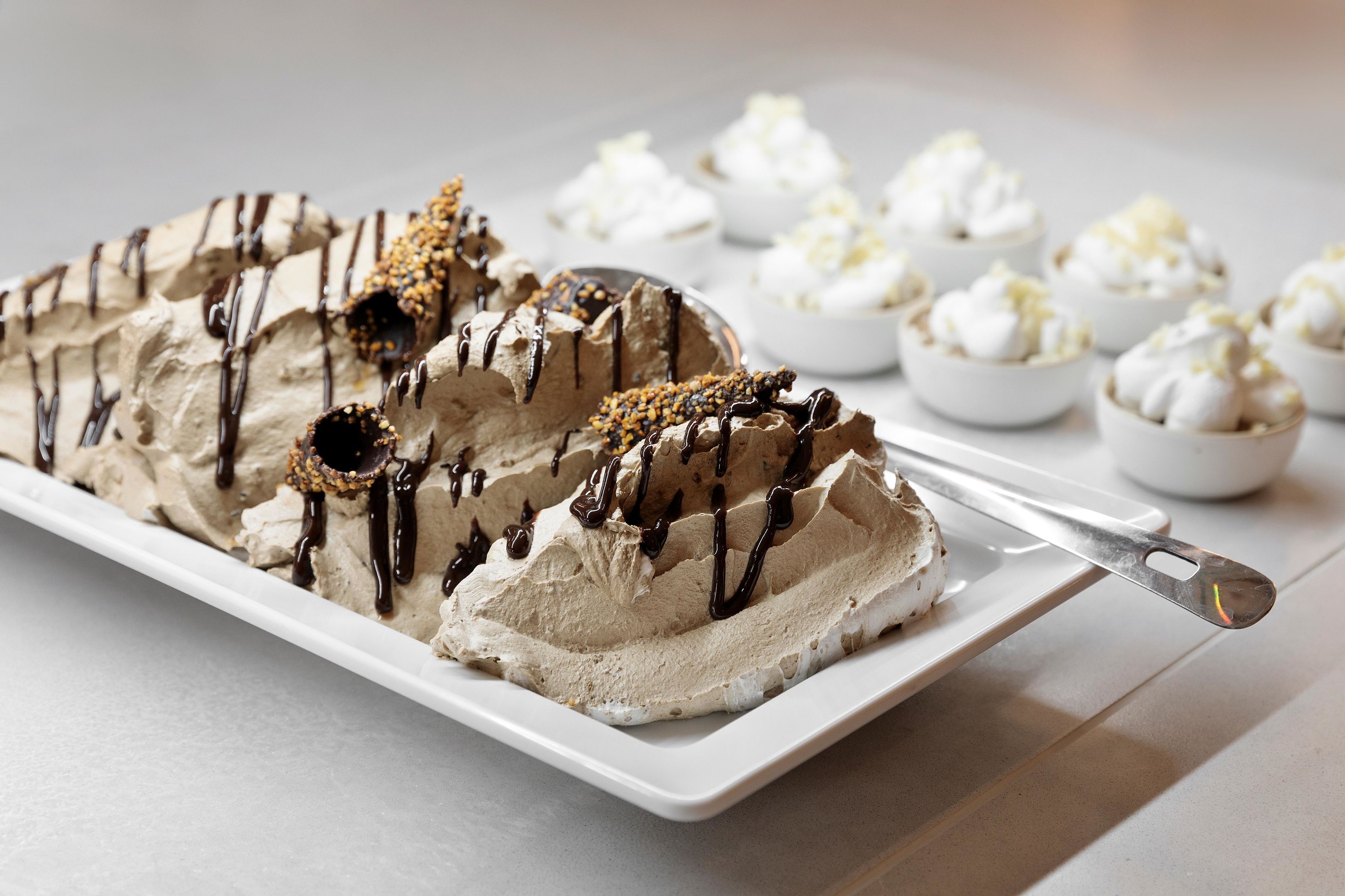 A dessert platter with chocolate mousse and whipped cream, garnished with chocolate drizzle and nuts.