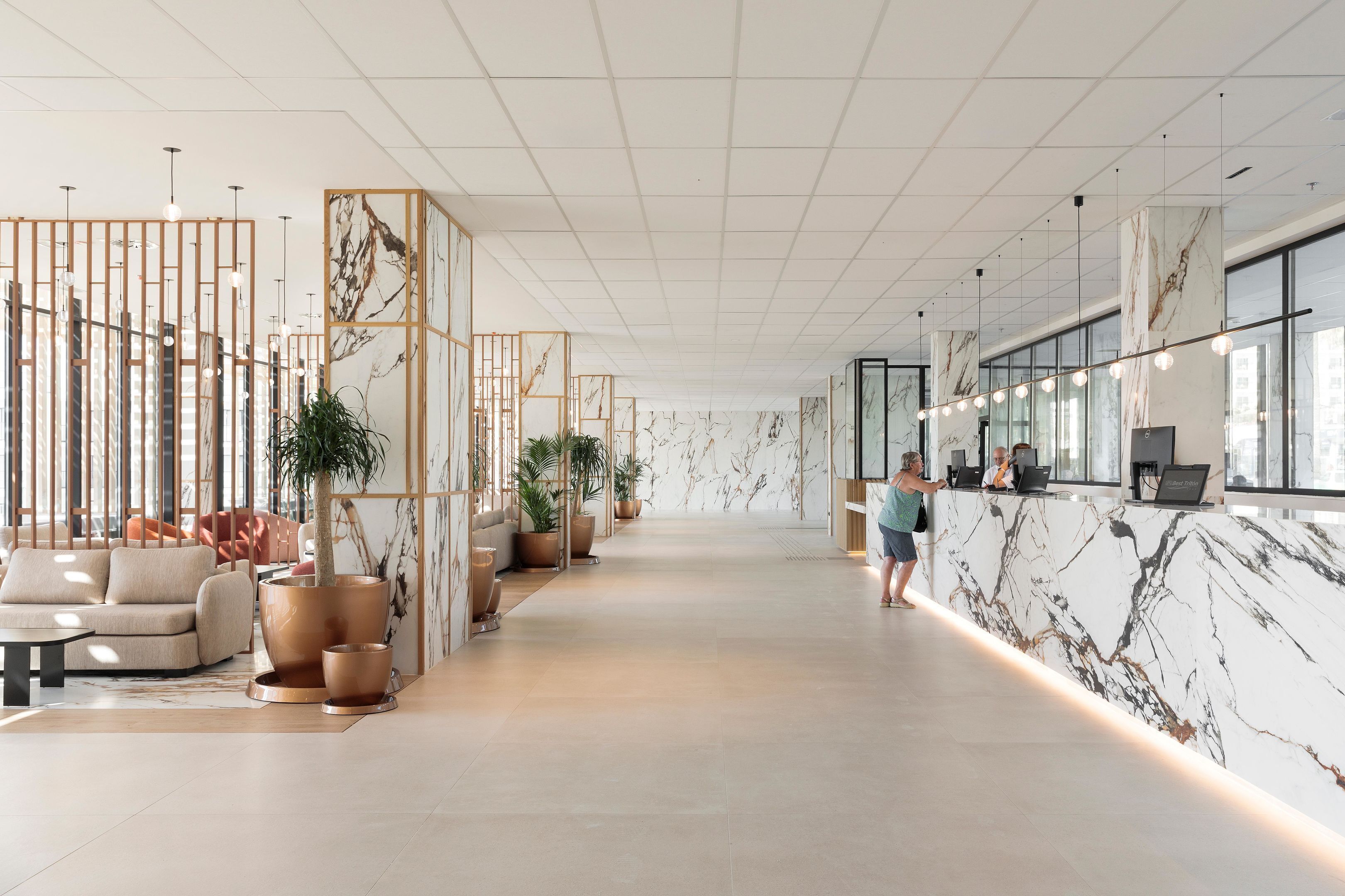 Un moderno vestíbulo de hotel con mostrador de recepción, zona de estar y grandes ventanales.