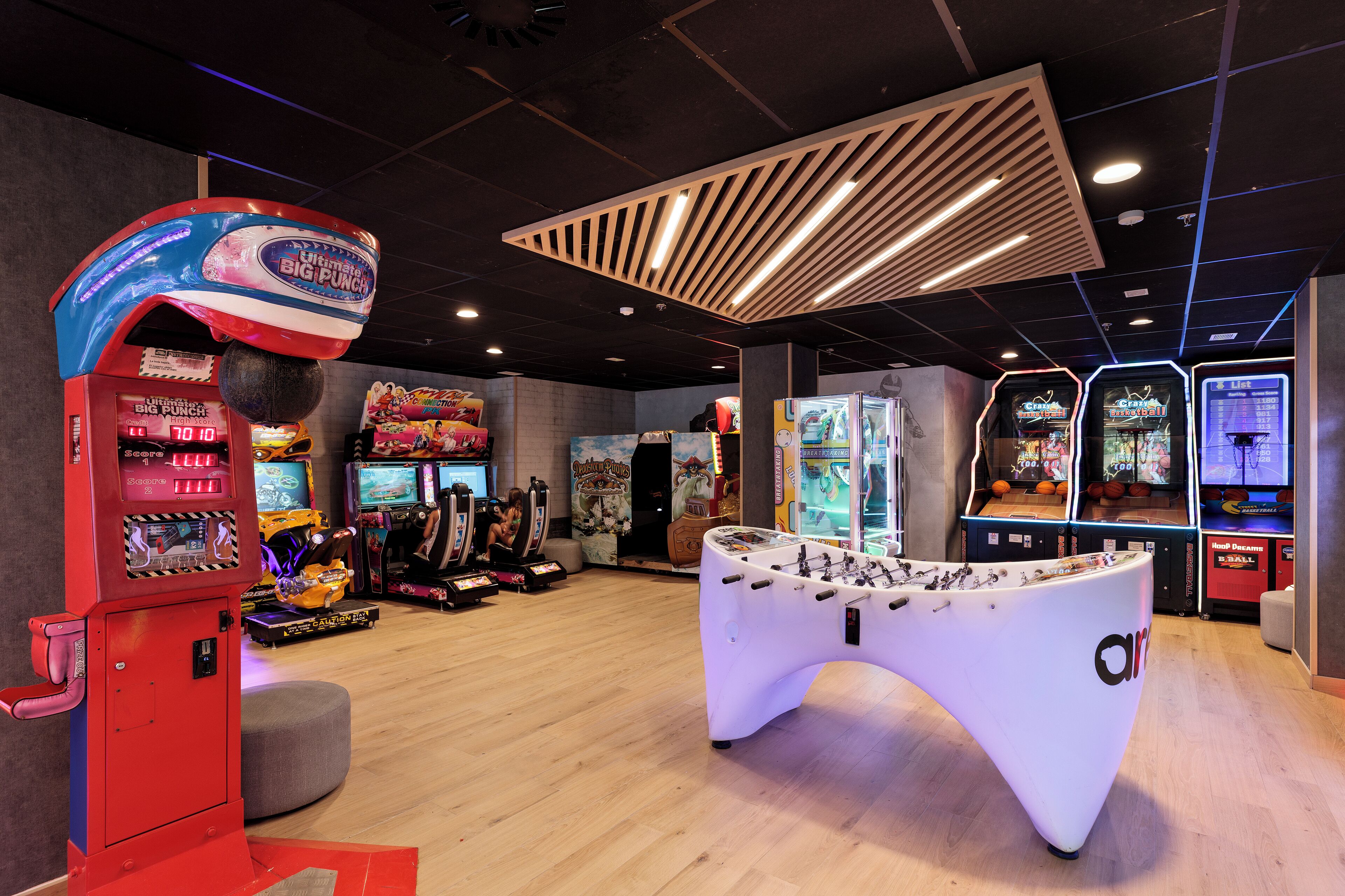 Un salón de juegos recreativos con diversas máquinas, incluyendo una mesa de fútbol de mesa y un juego de boxeo.