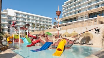 Un parque acuático con toboganes y temática de barco pirata, rodeado de edificios de hotel.