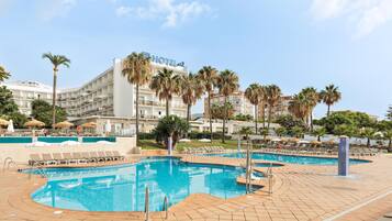 Un hotel con piscina, palmeras y cielo despejado.