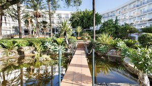 Un hotel con piscina, rodeado de plantas tropicales y palmeras.