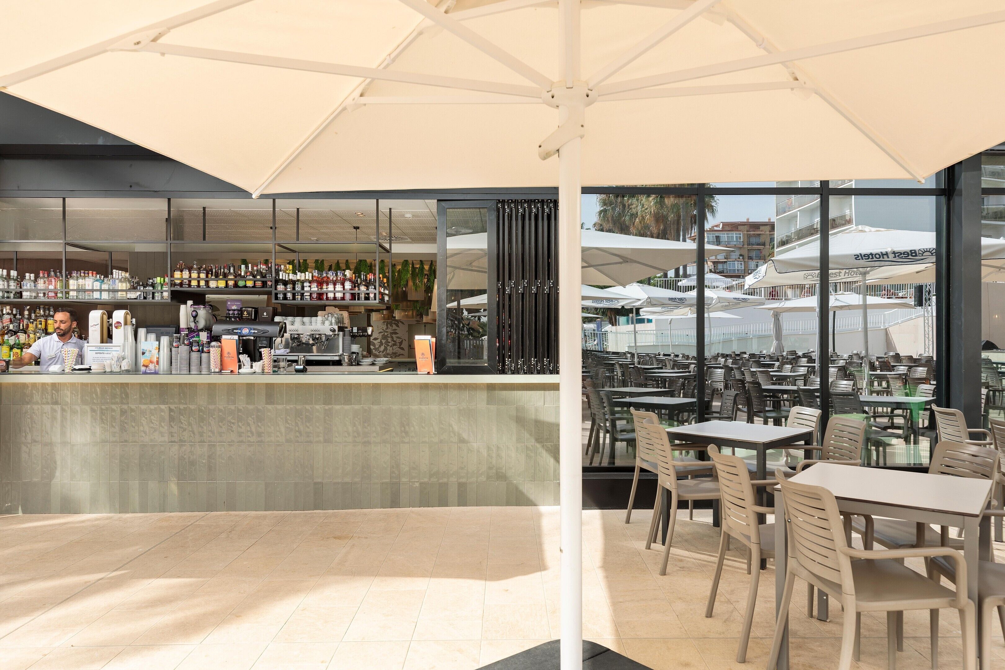 An outdoor bar area with a view of a building through large windows.