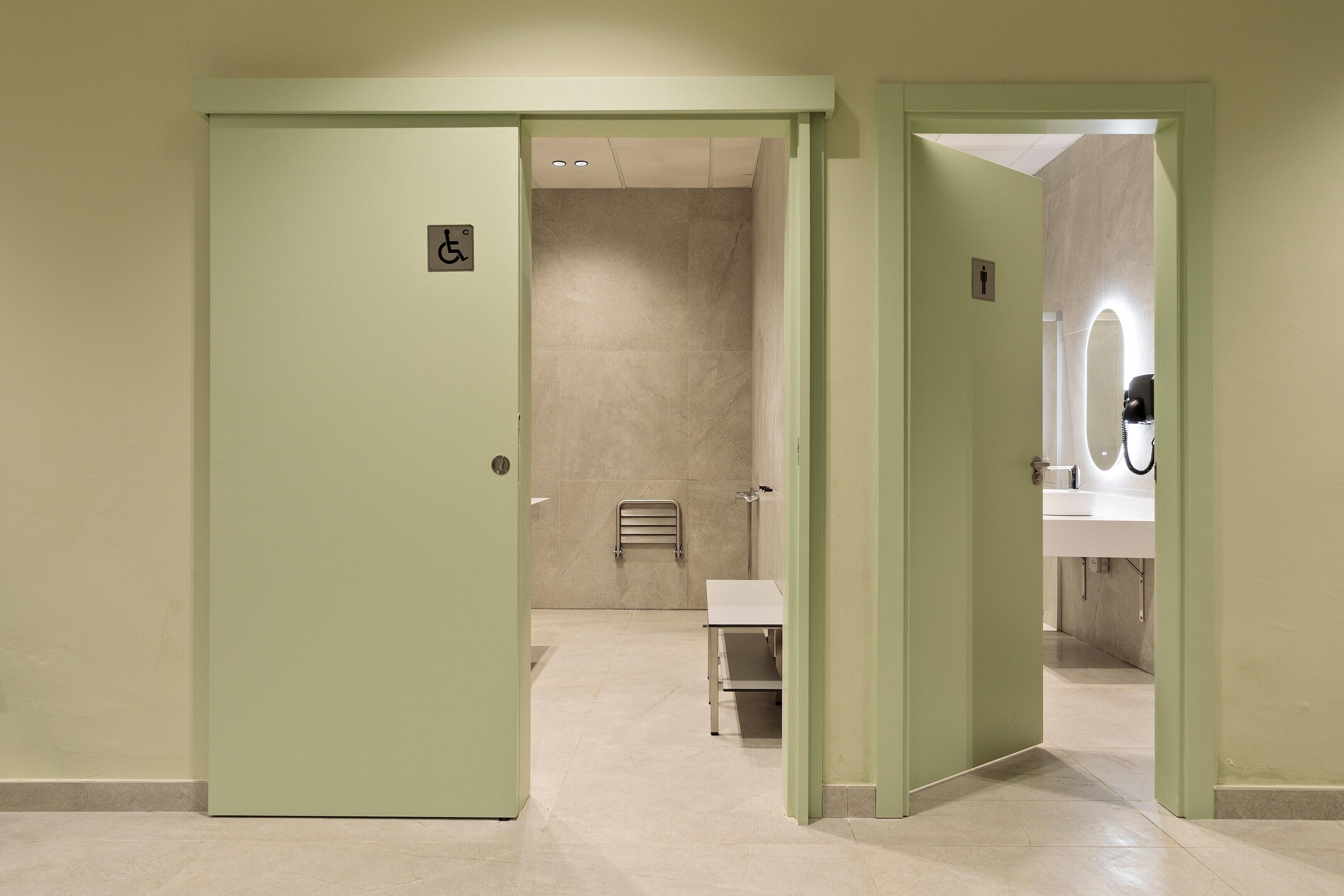 Un baño con señal de accesibilidad para sillas de ruedas, un perchero y un lavamanos.