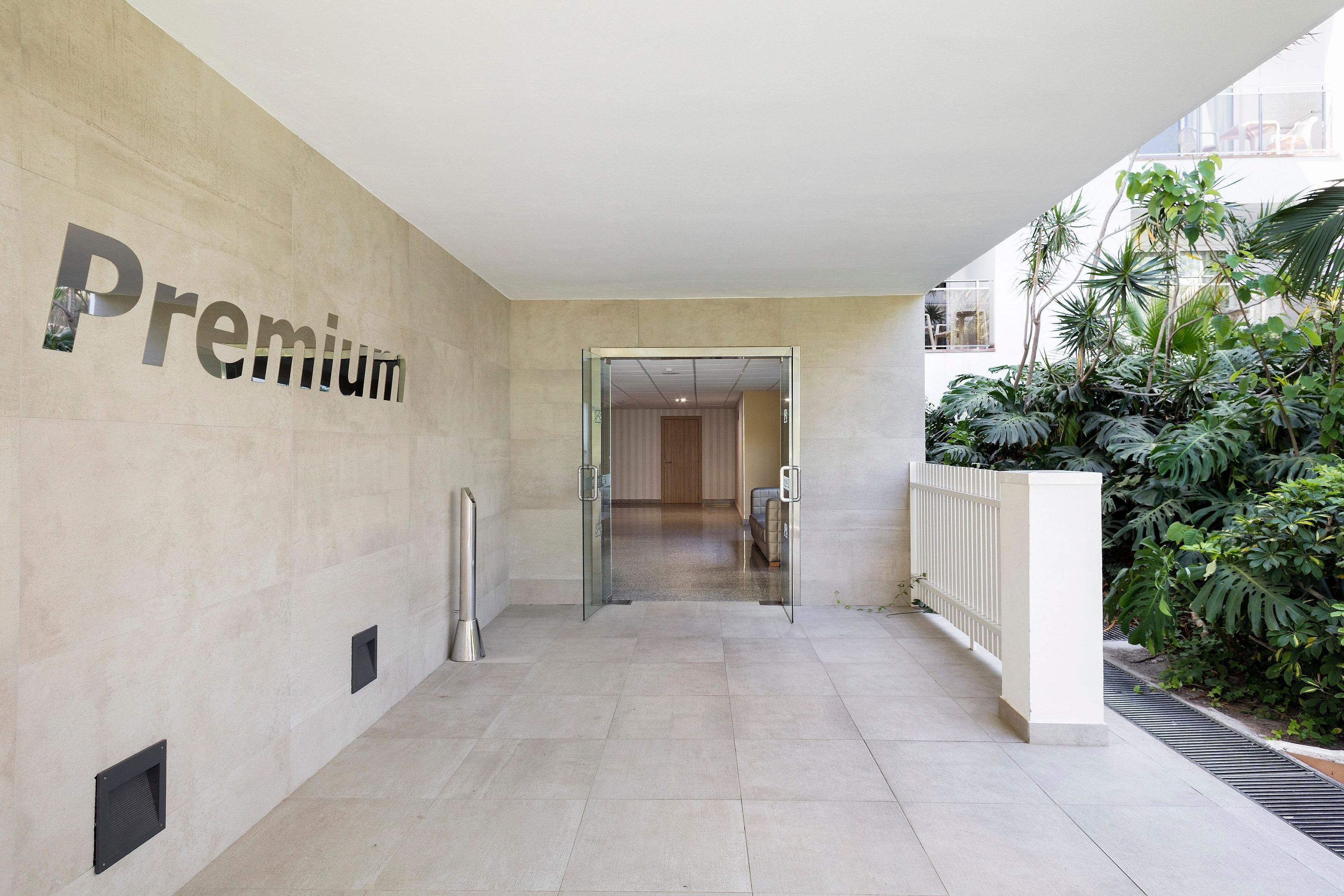 Un pasillo con un letrero que dice 'Premium', que conduce a una habitación con vistas a un balcón y plantas de interior.