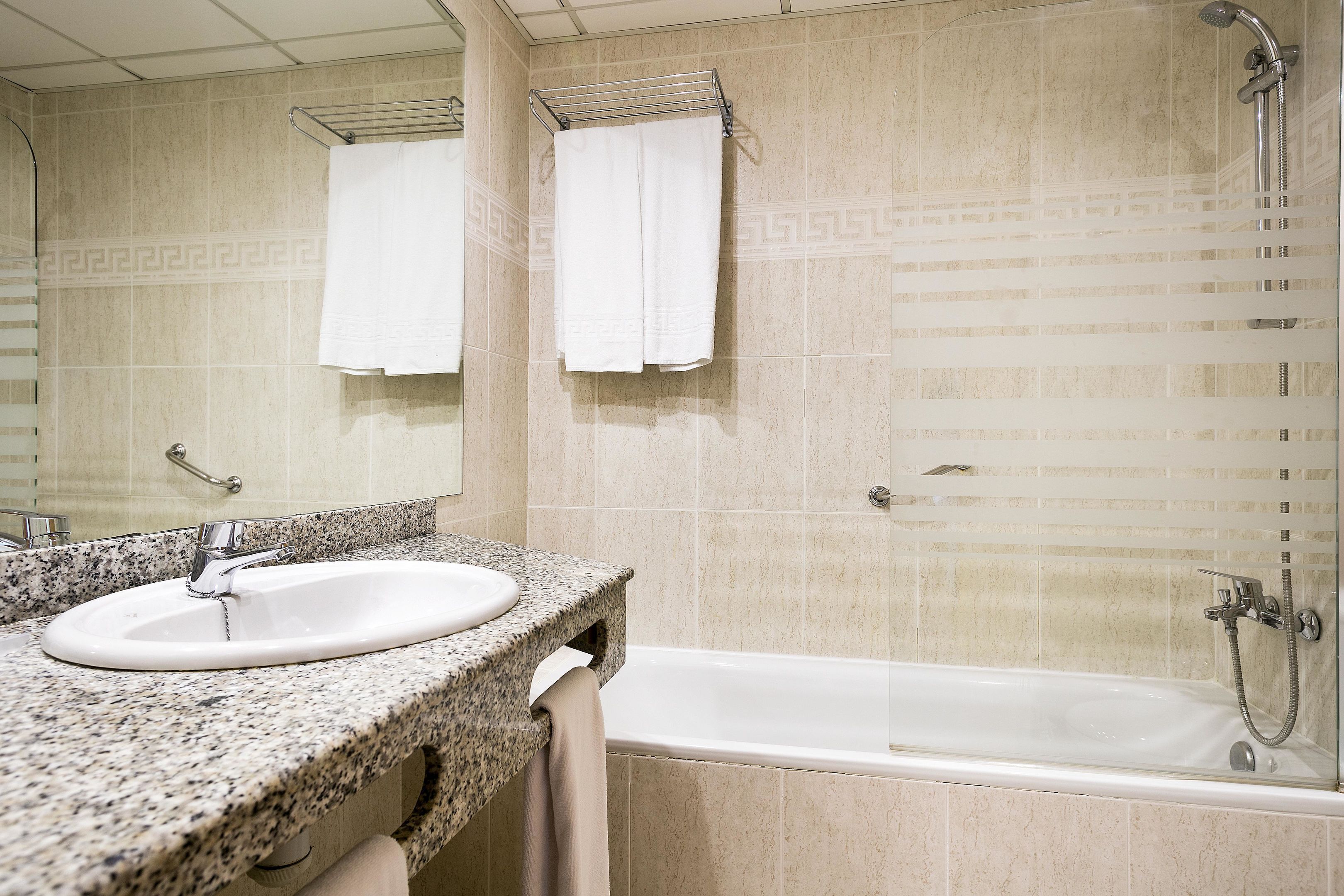 Un baño con lavabo, espejo, toallero y bañera.