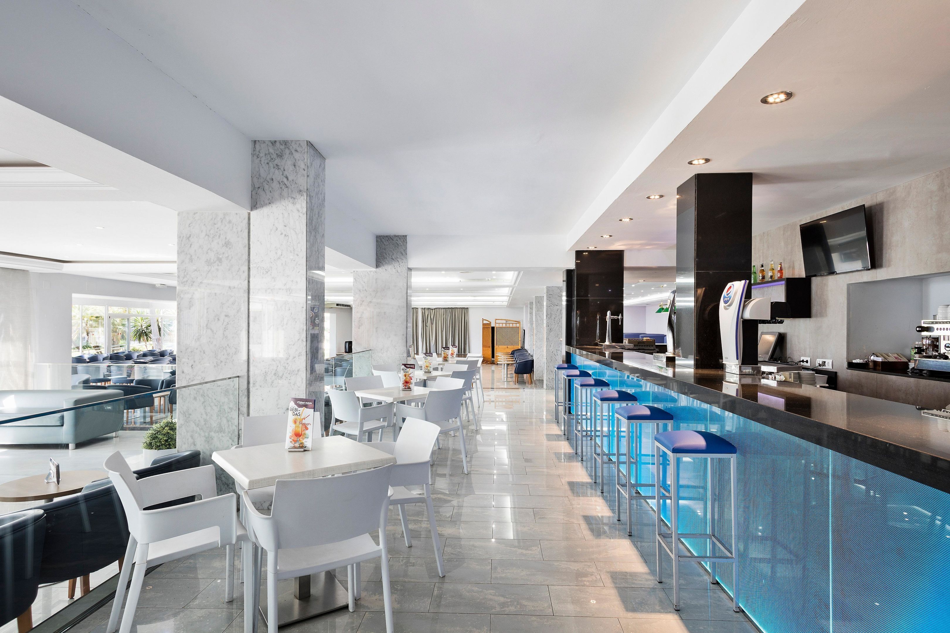 A modern hotel lobby with a bar area, seating arrangements, and a poolside bar.