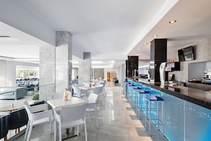 Un moderno vestíbulo de hotel con zona de bar, áreas de estar y bar junto a la piscina.