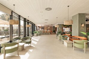 Amplio espacio interior con arreglos de asientos, una mesa de recepción y grandes ventanales que permiten la entrada de luz natural.