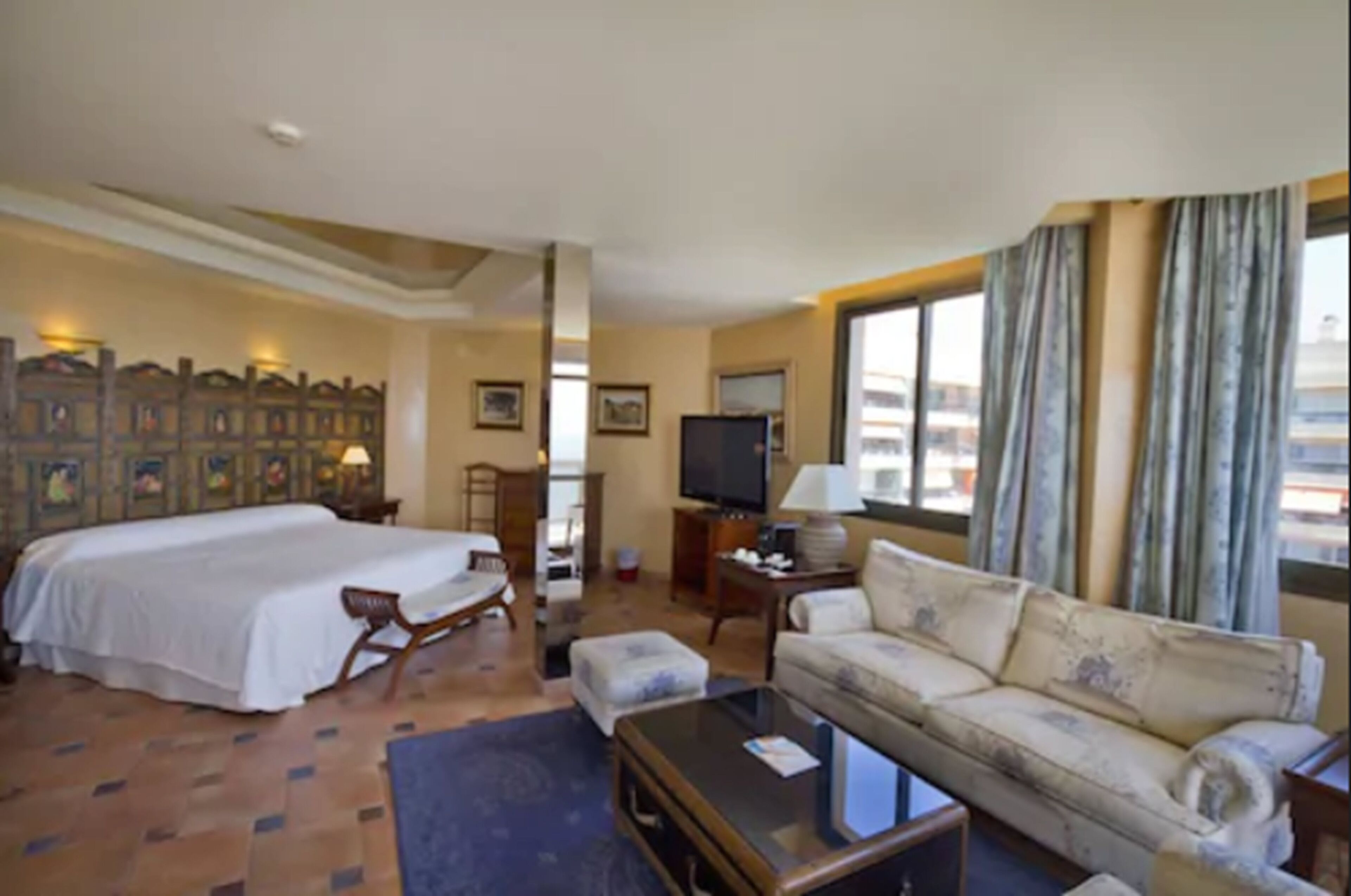 Une chambre d’hôtel avec un grand lit, un canapé, une télévision et une vue sur la ville.