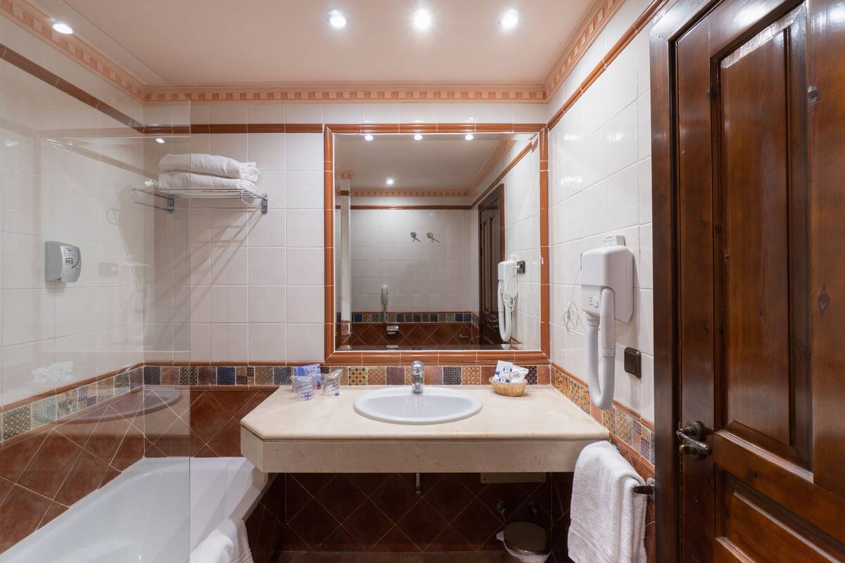 A bathroom with a bathtub, a sink, a mirror, and a shower.