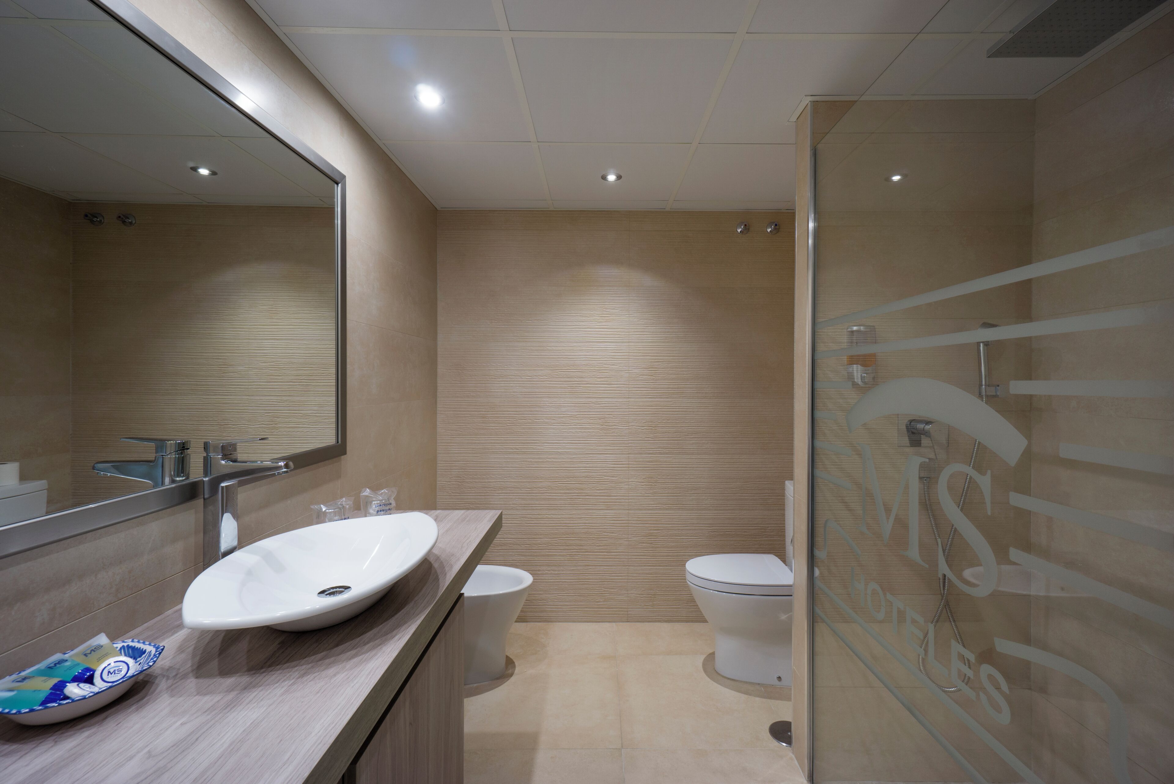 Un baño moderno con un espejo grande, un lavabo, un inodoro y una cabina de ducha de vidrio.