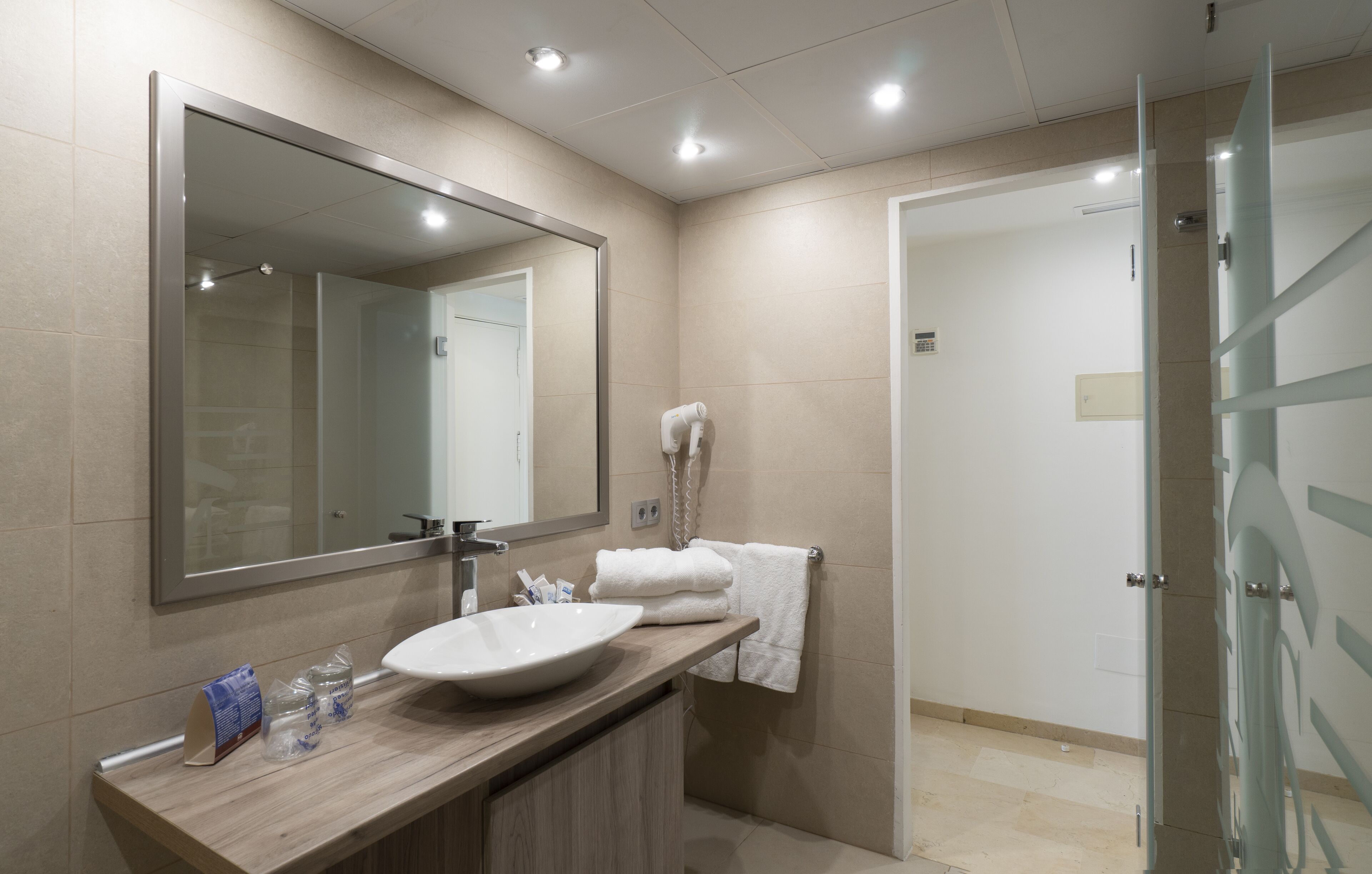 Un baño moderno con un espejo grande, un lavabo y una cabina de ducha de vidrio.