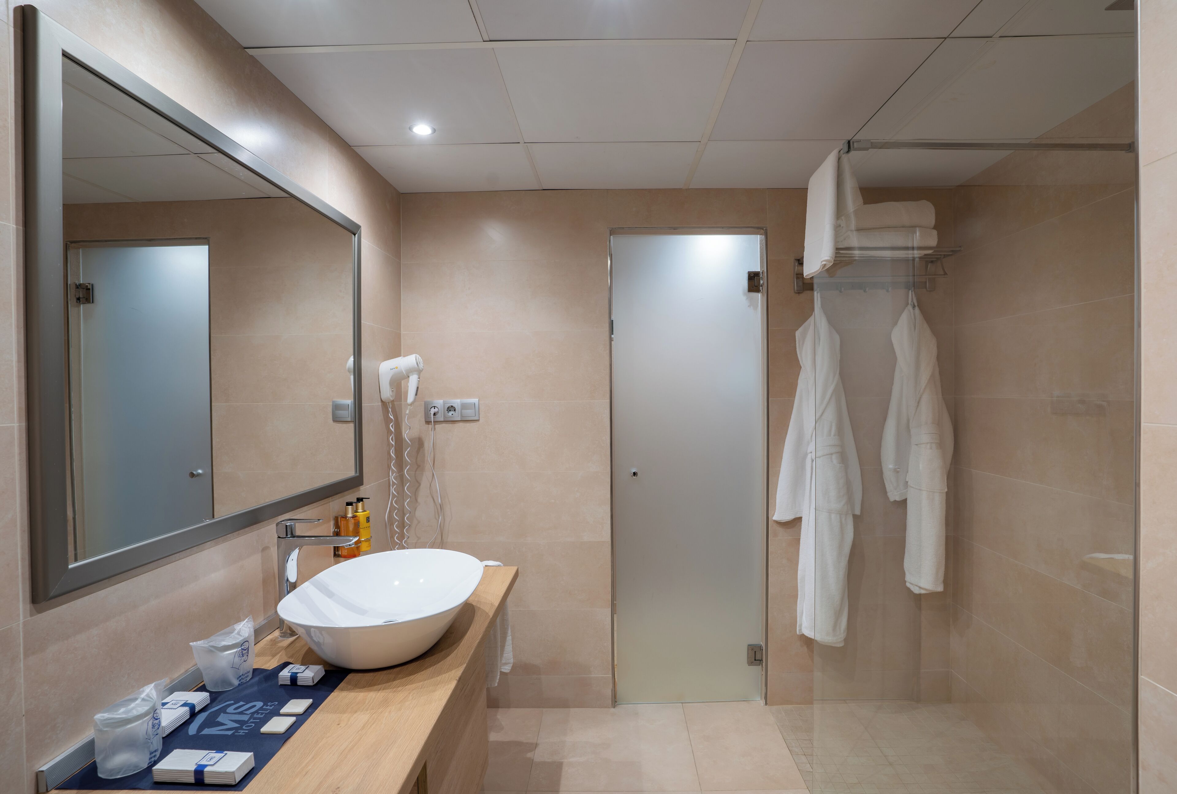 A modern bathroom with a large mirror, a white sink, and a glass shower enclosure.