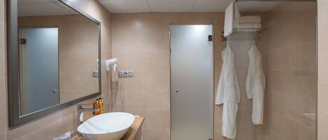 A modern bathroom with a large mirror, a white sink, and a glass shower enclosure.