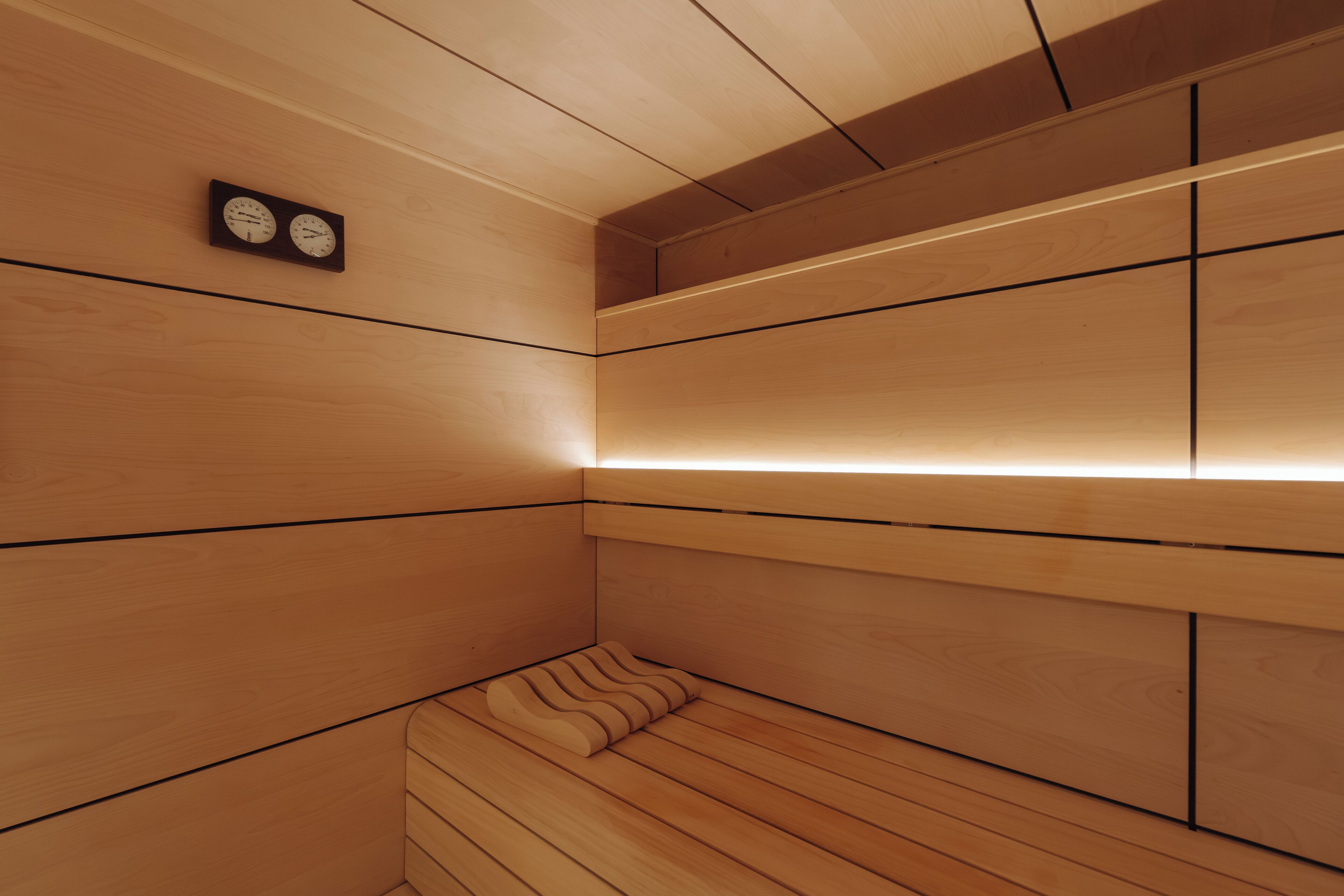 Una habitación de madera con un banco, un reloj y una estantería.