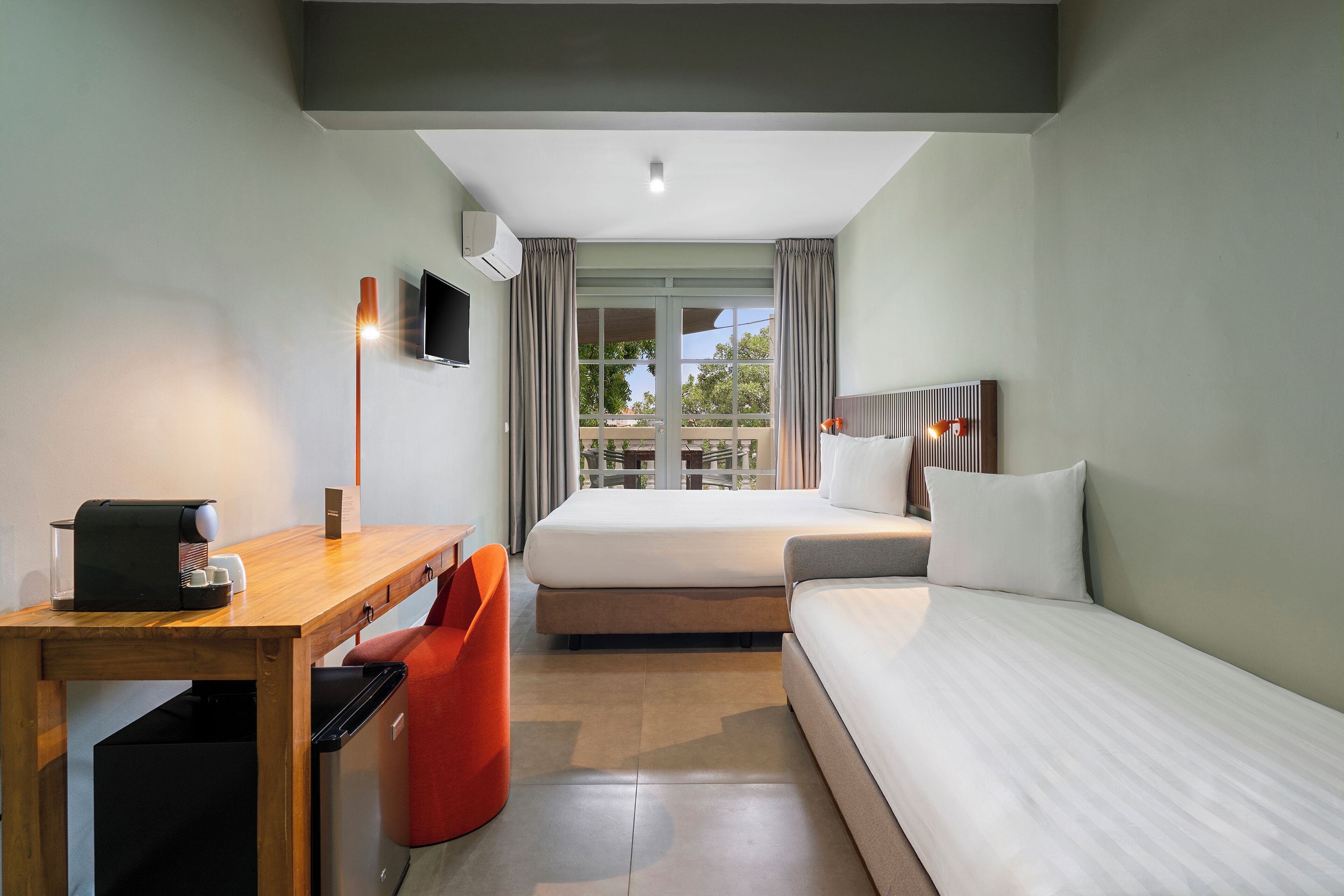Ein Hotelzimmer mit einem Bett, einem Schreibtisch mit Kaffeemaschine, einem Fernseher und Blick ins Freie.