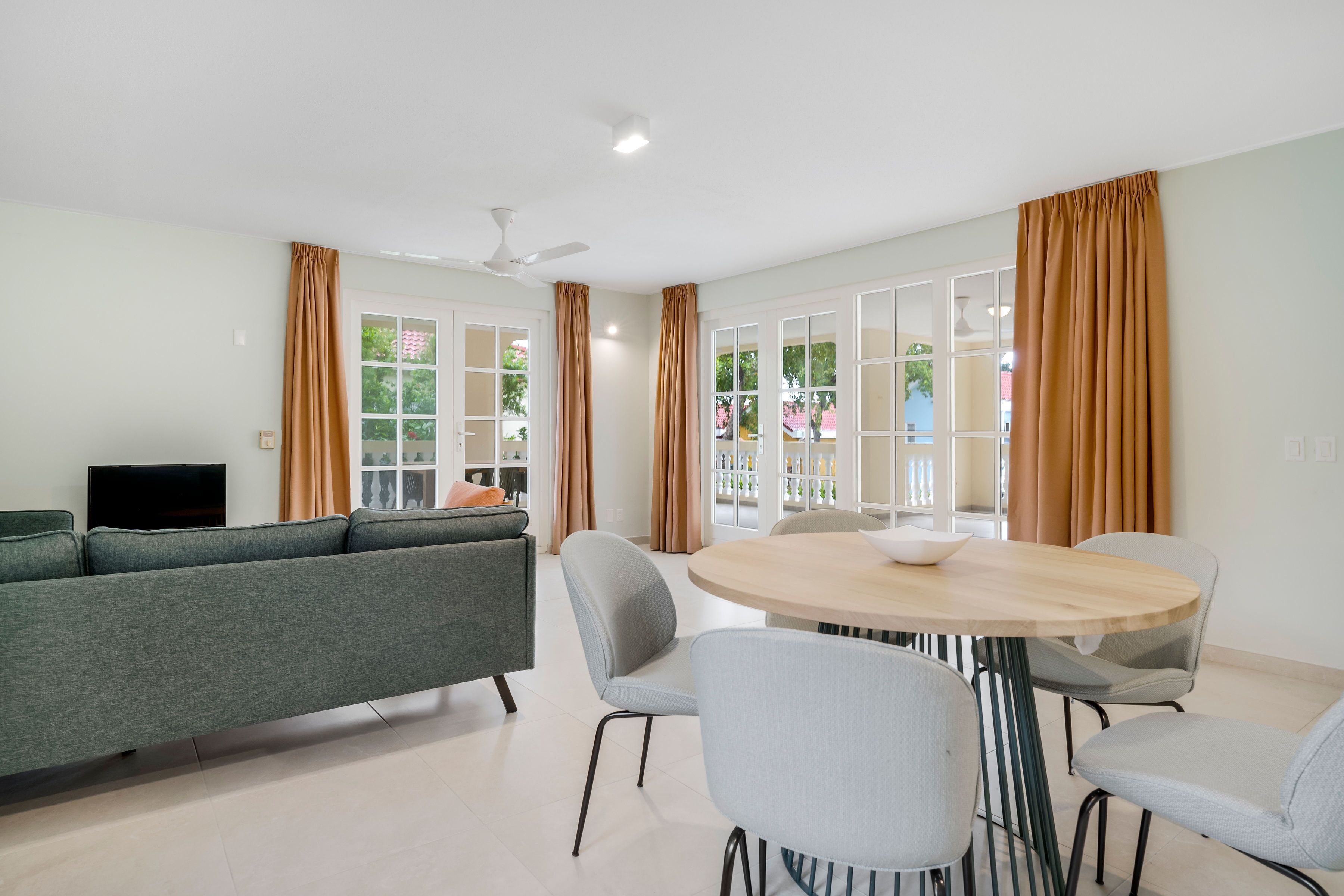 A modern living room with a grey sofa, a round wooden dining table, and grey chairs.