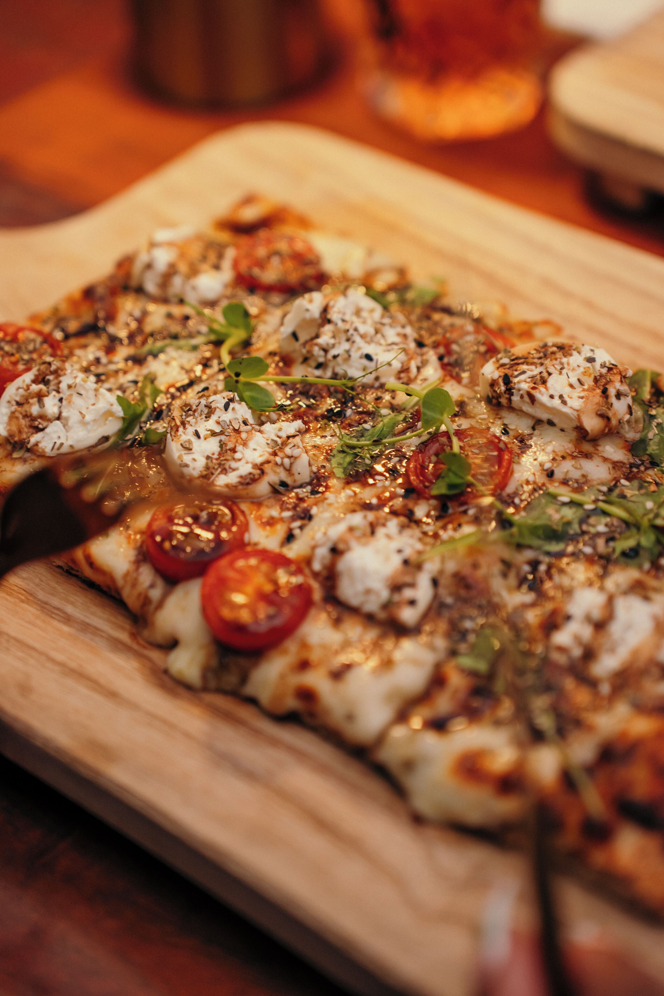 A pizza with toppings on a wooden board.