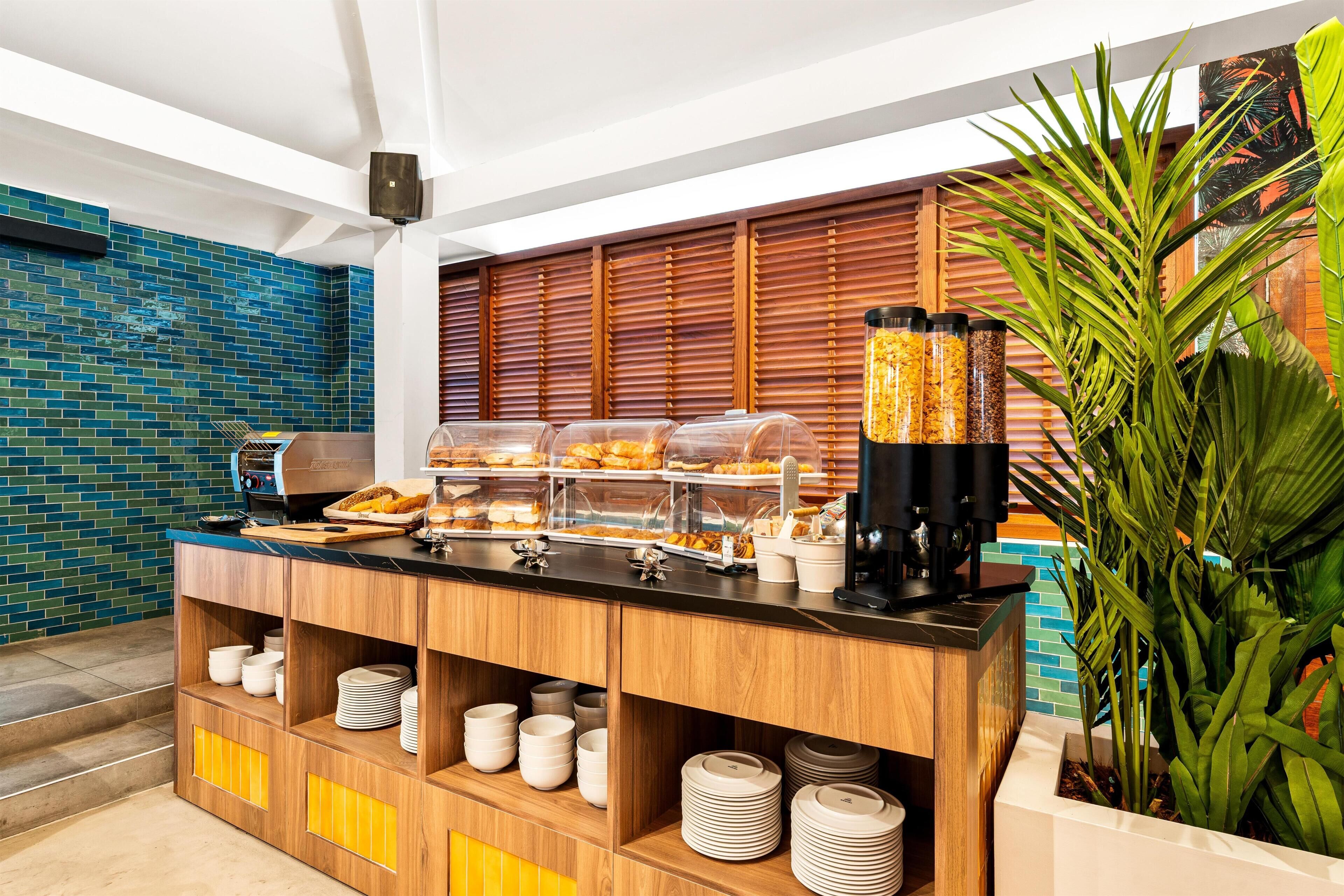 A buffet area with a coffee station, a variety of food items, and a plant.