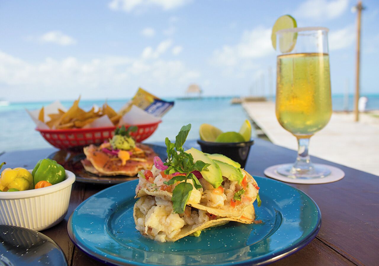 Un repas accompagné d’une boisson, servi sur une table au bord de la plage.
