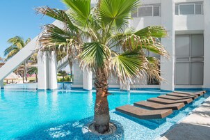 Una piscina al aire libre, camas de piscina con cargo, sombrillas