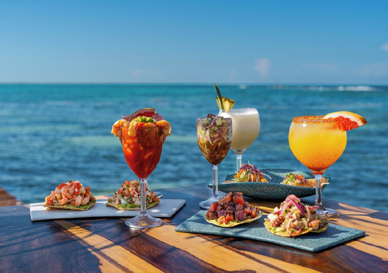 A table with seafood dishes and drinks by the ocean.