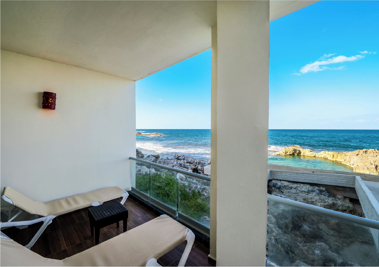 Un balcon avec deux fauteuils de relaxation, une petite table et une vue sur l’océan.