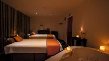 A hotel room with two beds, a large bathtub, and a mirror.