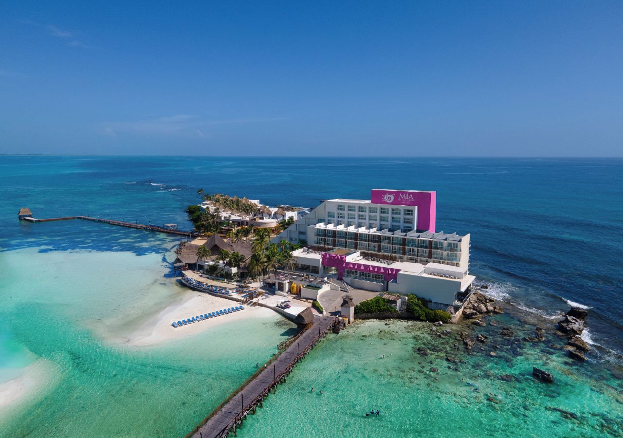 A resort with a beach, a pier, and a building with a pink sign.