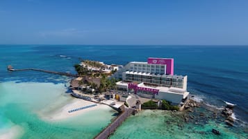 A resort with a beach, a pier, and a building with a pink sign.