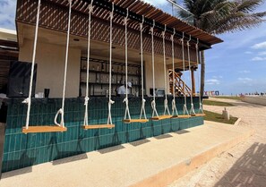 A beachside bar with a wooden pergola, a tiled wall, and a palm tree in the background. - Mia Reef Isla Mujeres - All Inclusive (Isla Mujeres)