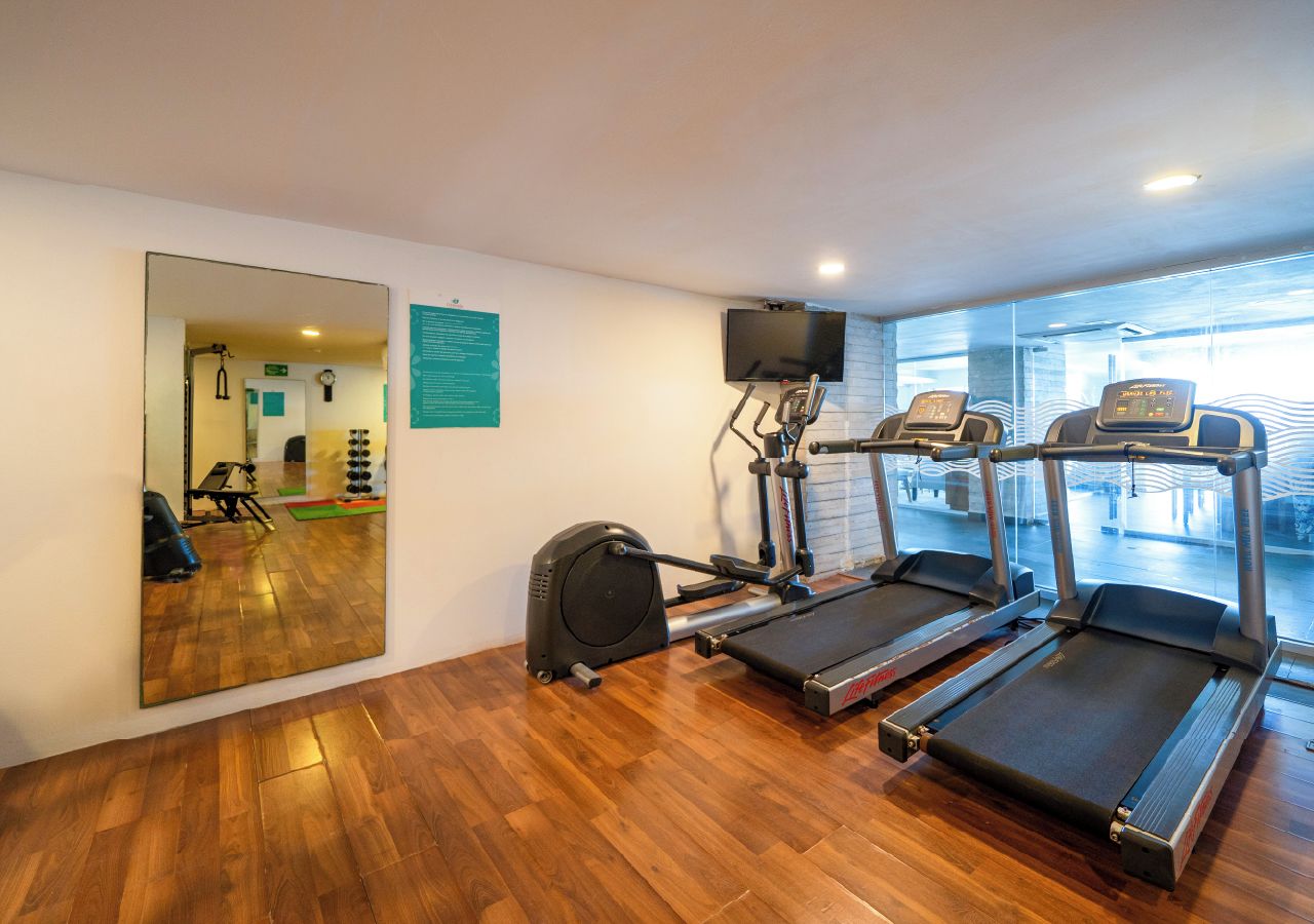 A gym with treadmills, a stationary bike, and a mirror reflecting the room.