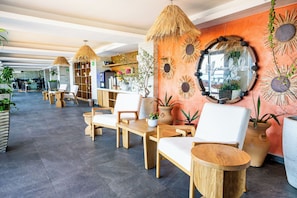 A modern hotel lobby with wooden furniture, a reception desk, and decorative sunburst mirrors.