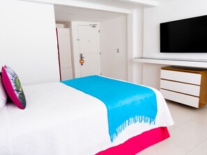 A bedroom with a bed, a TV, a wardrobe, and a door.