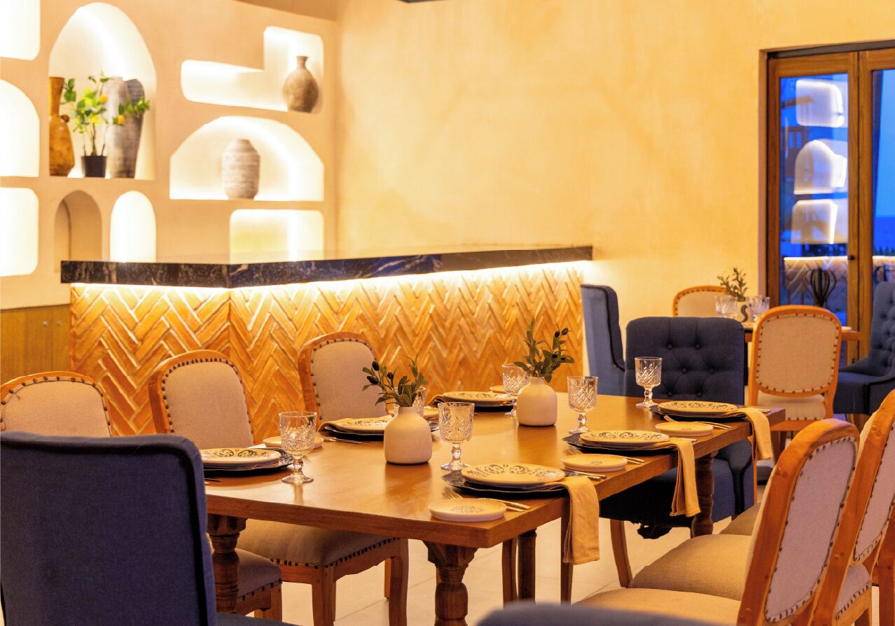 Un comedor con un revestimiento mural en patrón de espiga, mesas de madera y sillas tapizadas.