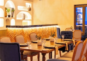 Un comedor con un revestimiento mural en patrón de espiga, mesas de madera y sillas tapizadas.
