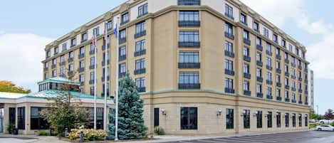 A large, multi-story hotel with a curved facade, multiple balconies, and a parking lot in front.