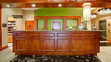 A reception area with a wooden counter, green walls, and a chandelier.