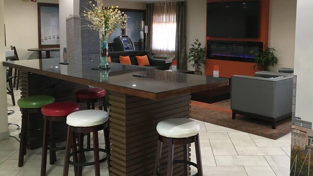 Zona de bar moderna amb un mostrador de bar amb tapa de vidre, diversos tamborets, una màquina recreativa i un televisor de pantalla plana.